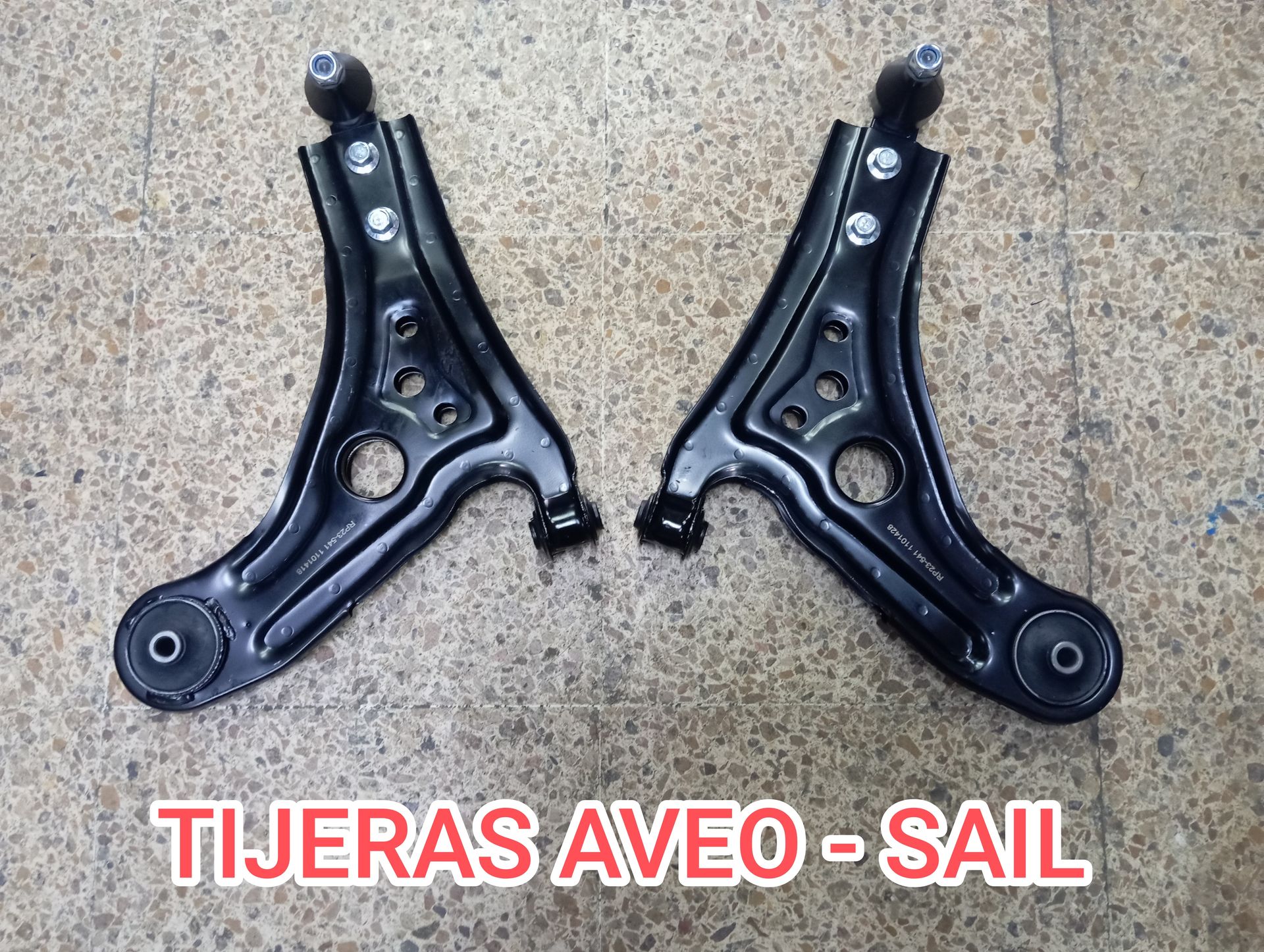 Par de tijeras de suspensión negras para Aveo-Sail sobre fondo texturizado, con texto “TIJERAS AVEO-SAIL”