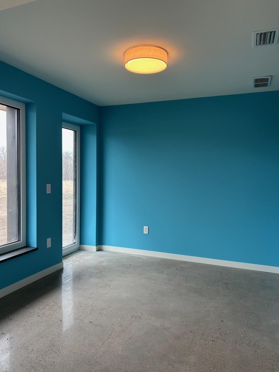An empty room with blue walls and a ceiling light