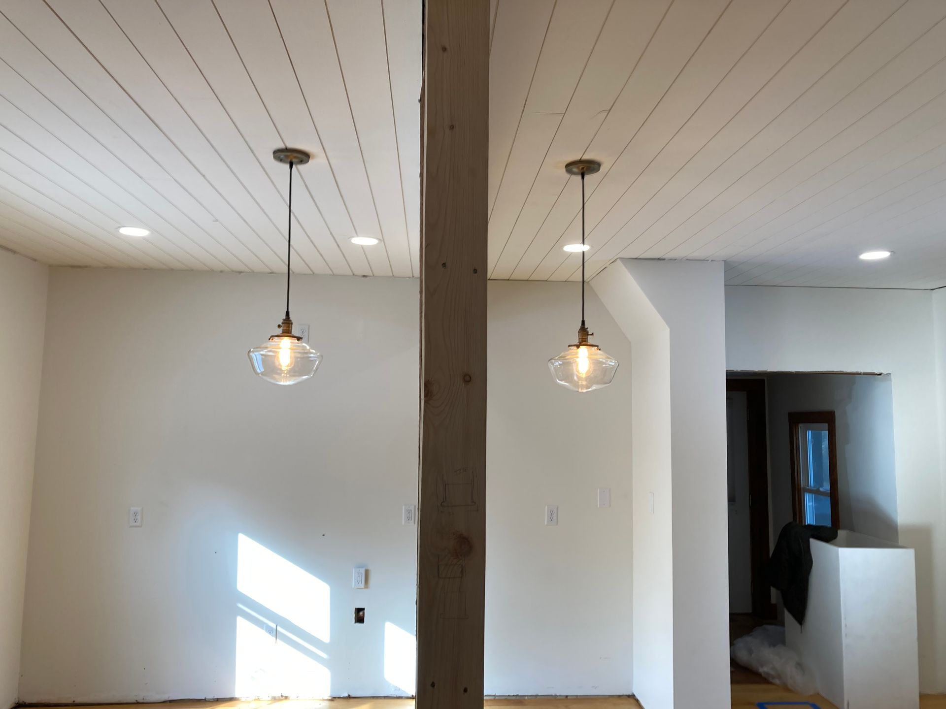 A room with a white ceiling and two pendant lights hanging from it