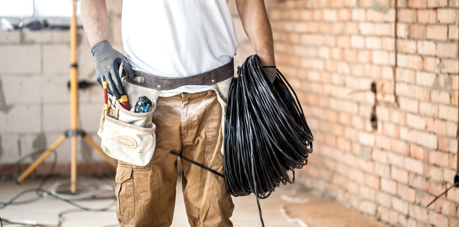 A man is holding a roll of wires in a room.