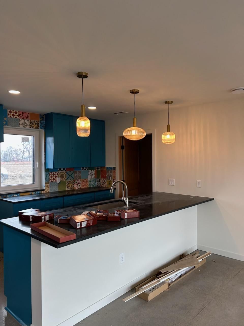 A kitchen with blue cabinets and a black counter top.