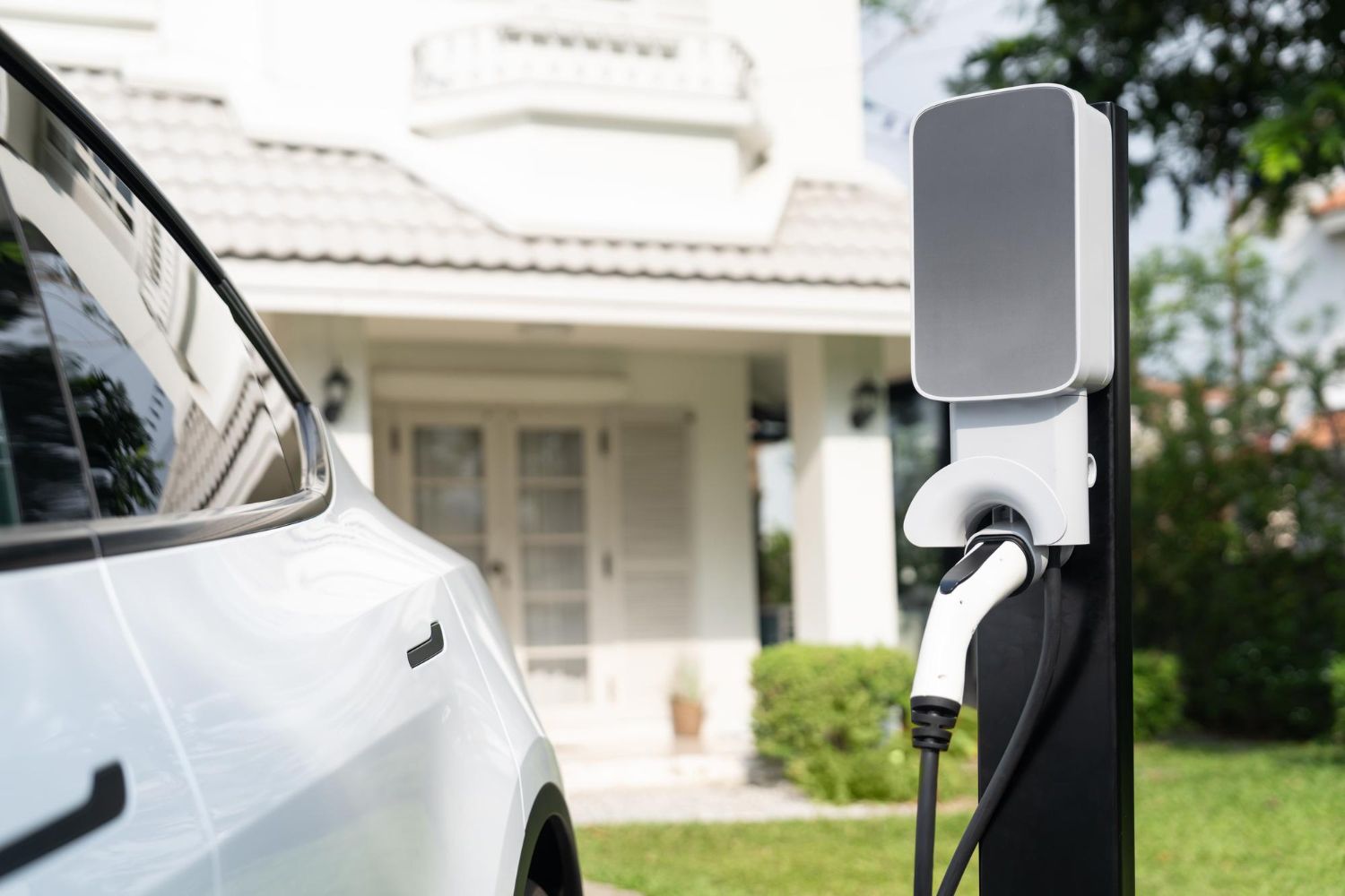 An electric car is being charged at a charging station in front of a house.