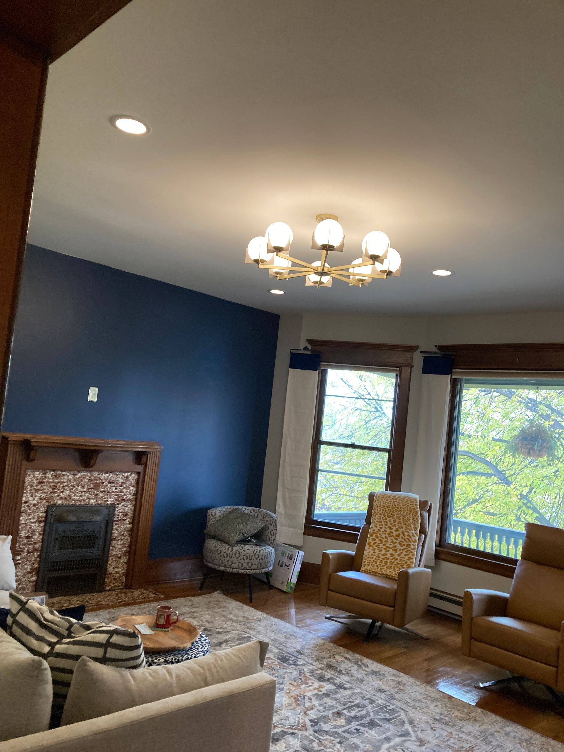 A living room with a fireplace , couch , chairs and a chandelier.