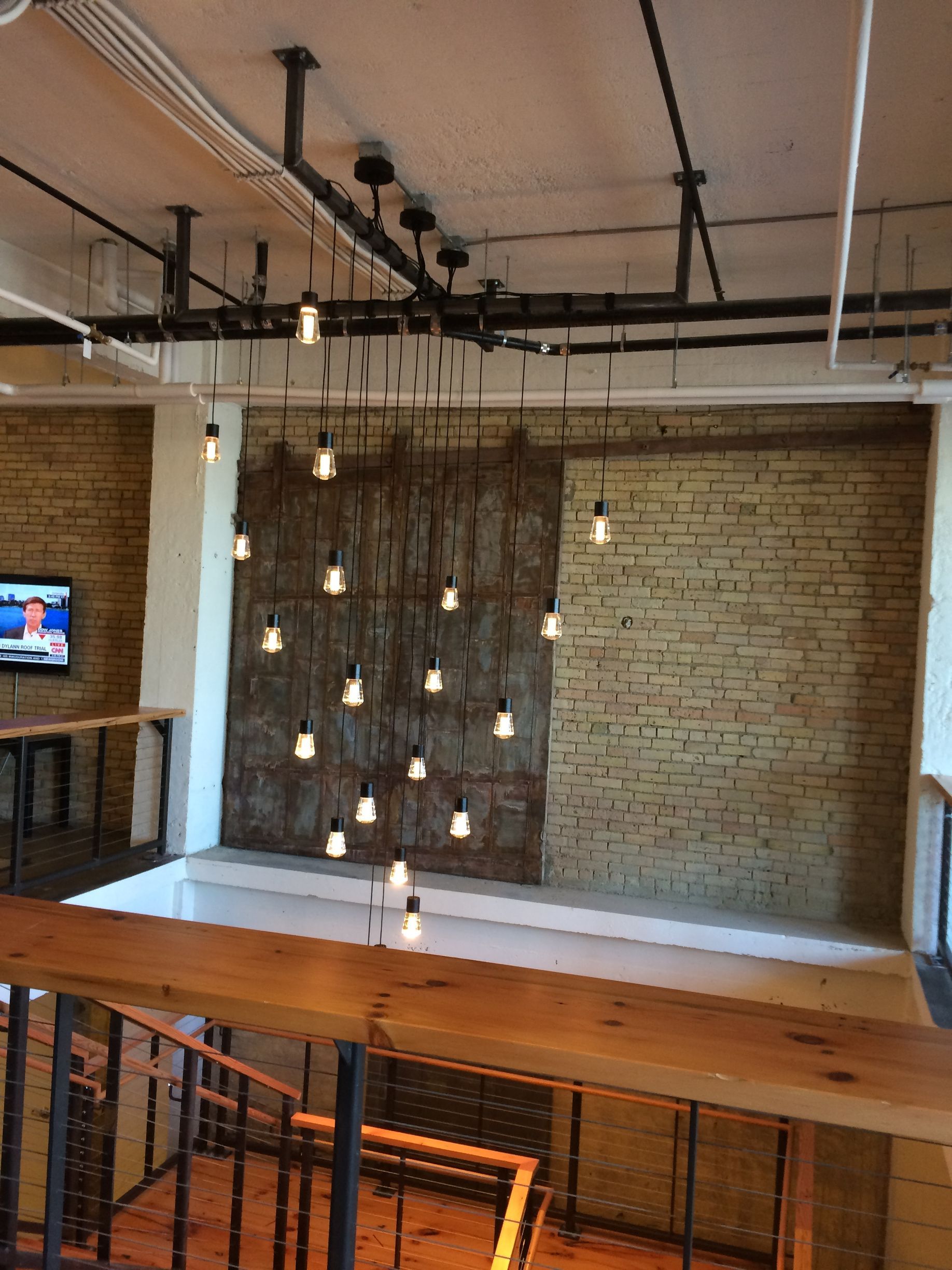 A room with a brick wall and lots of lights hanging from the ceiling