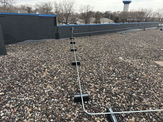 A roof with a lot of gravel and a tower in the background