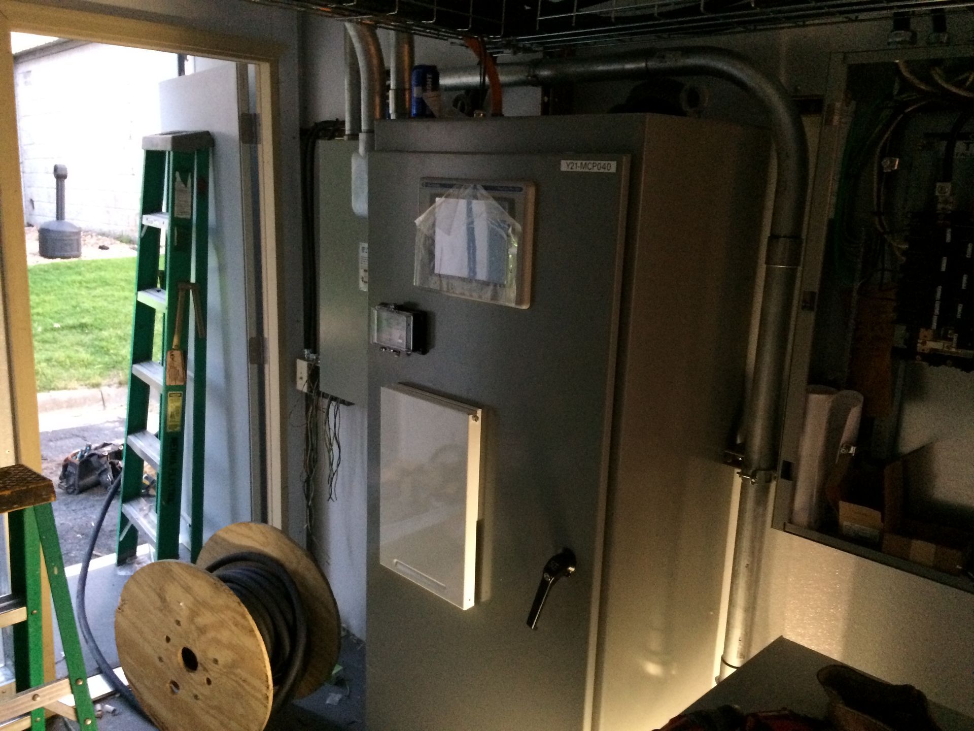 A large electrical box is sitting in a room next to a ladder.