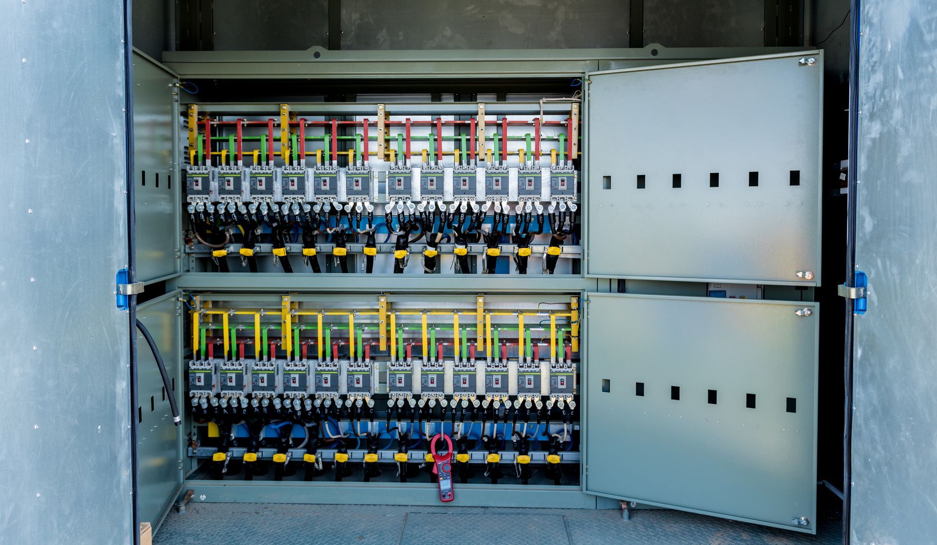 A large electrical box with the doors open and lots of wires coming out of it.