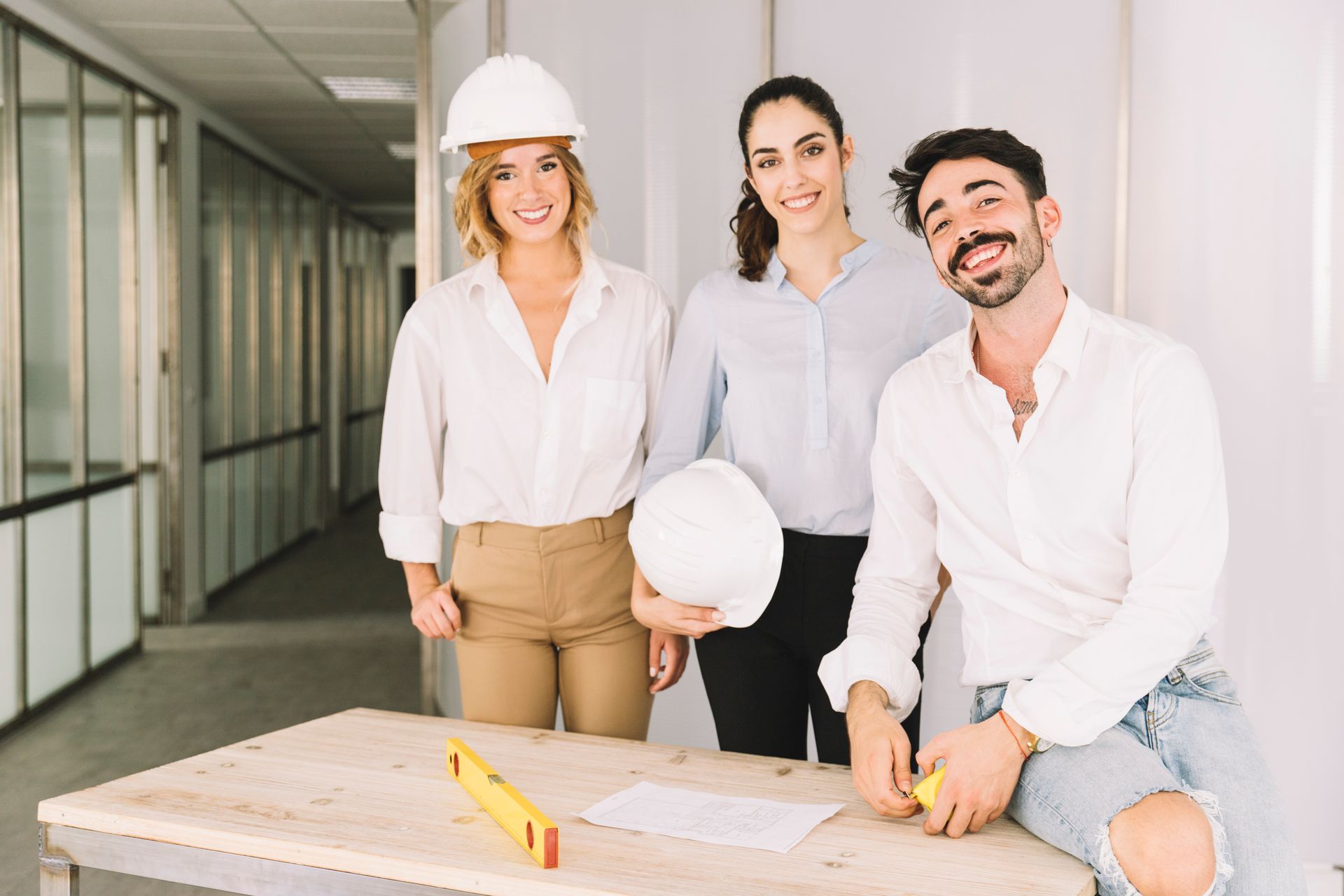 A man and two women are standing next to each other holding hard hats.