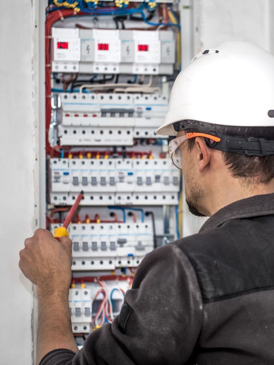 a man wearing a hard hat is working on a circuit board