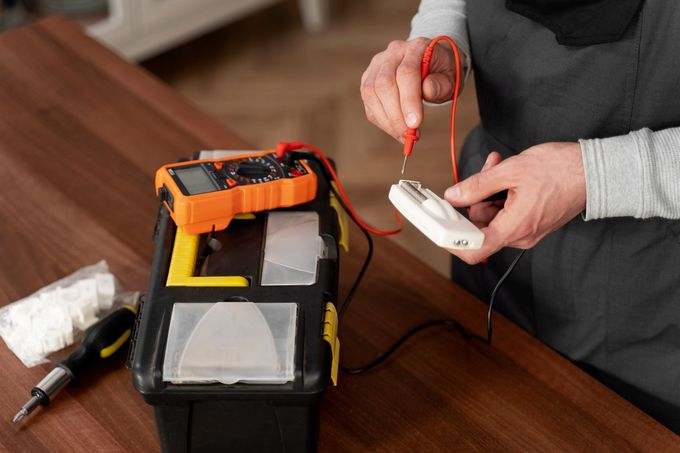 a man is working on an electrical outlet with a multimeter