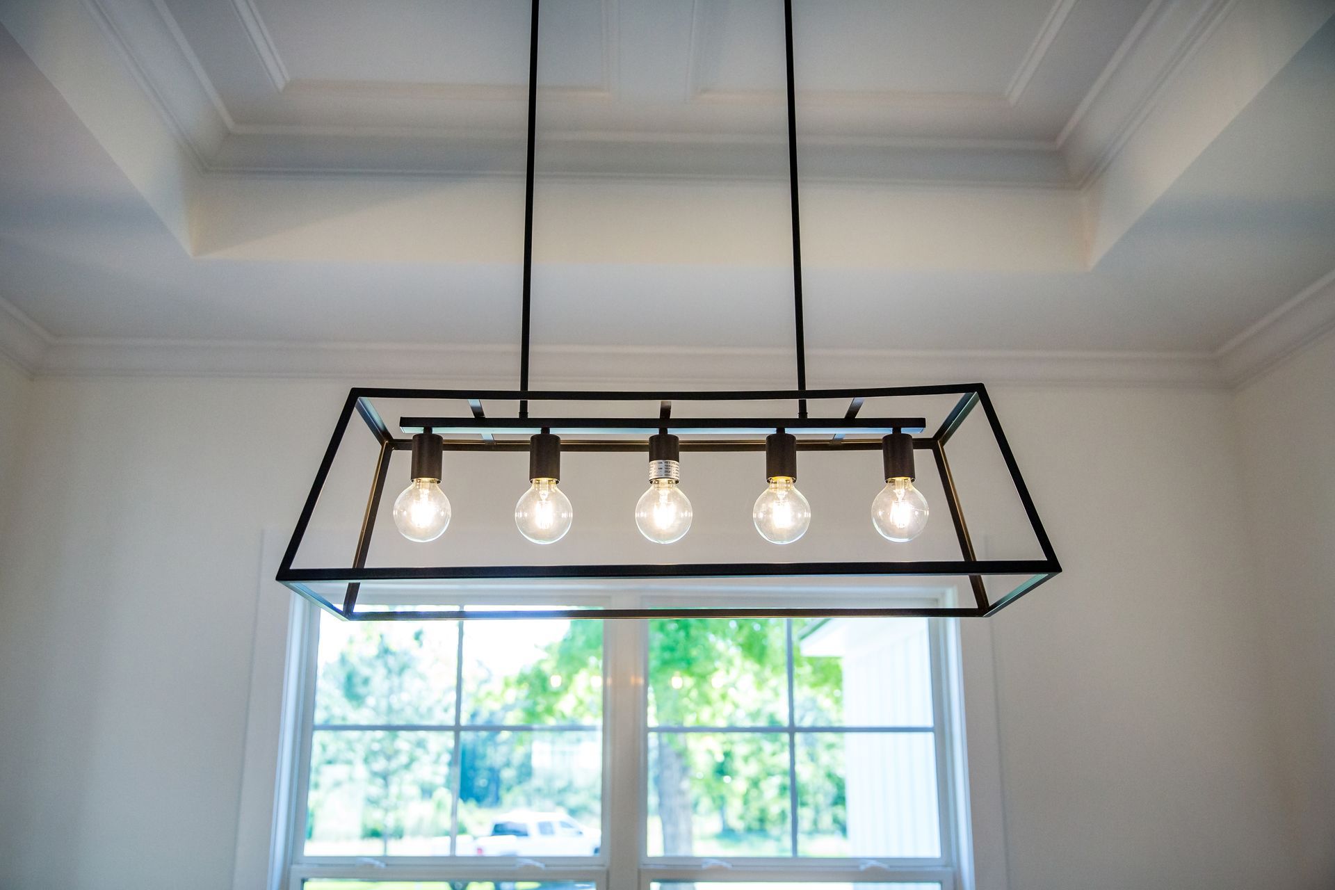 A chandelier is hanging from the ceiling in a room next to a window.