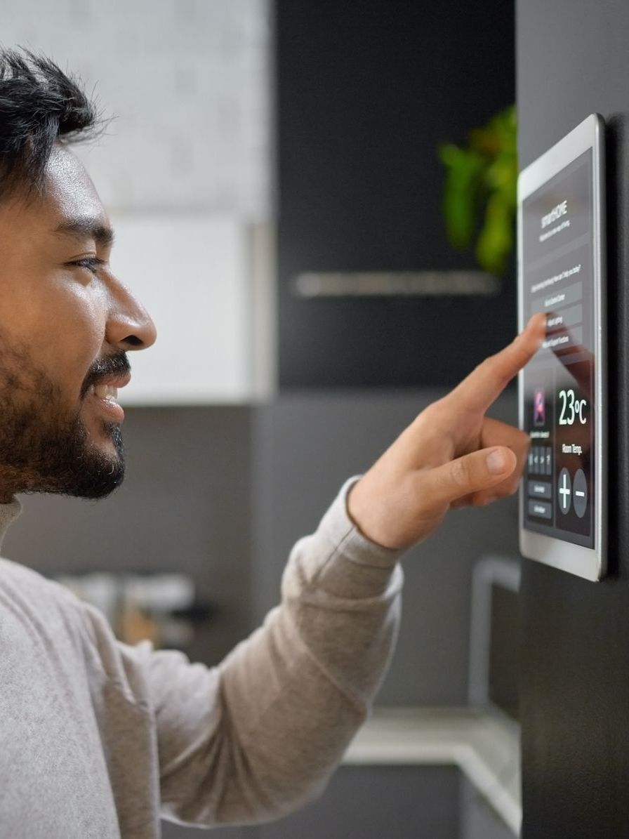 A man is pressing a button on a thermostat