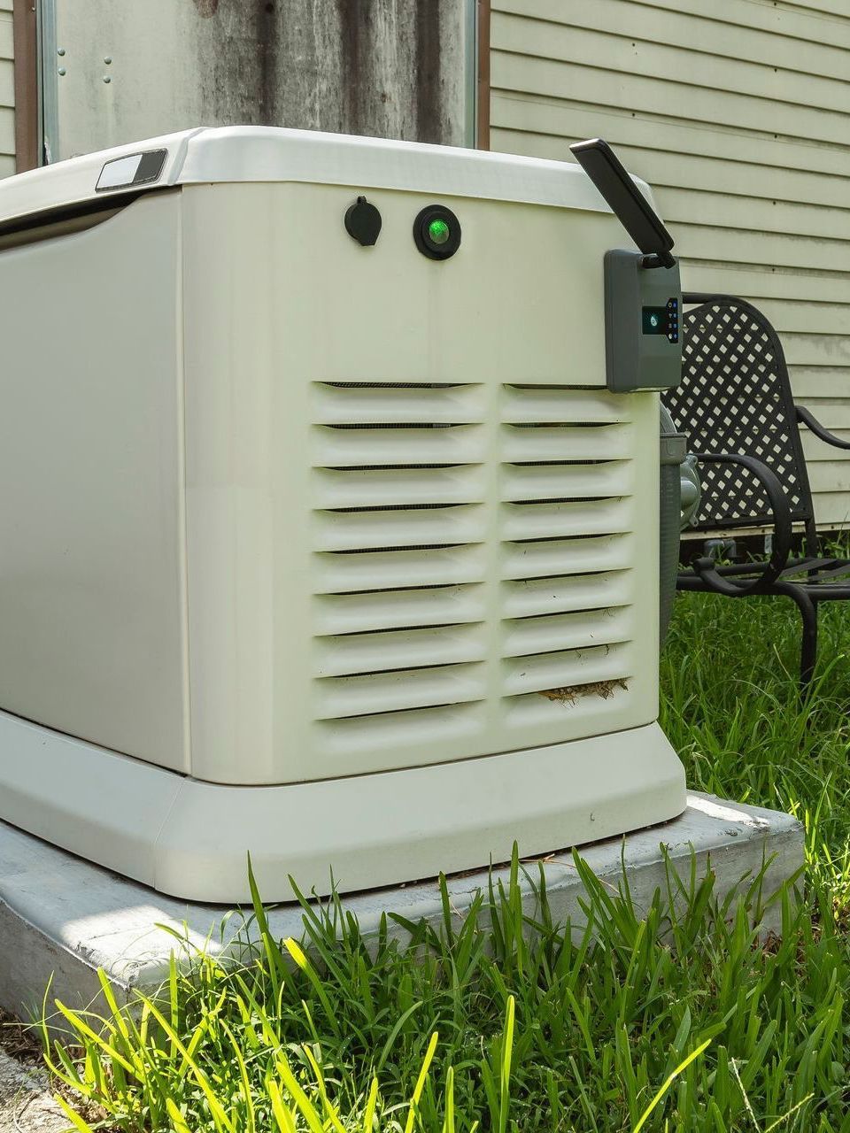 a white generator is sitting in the grass next to a chair