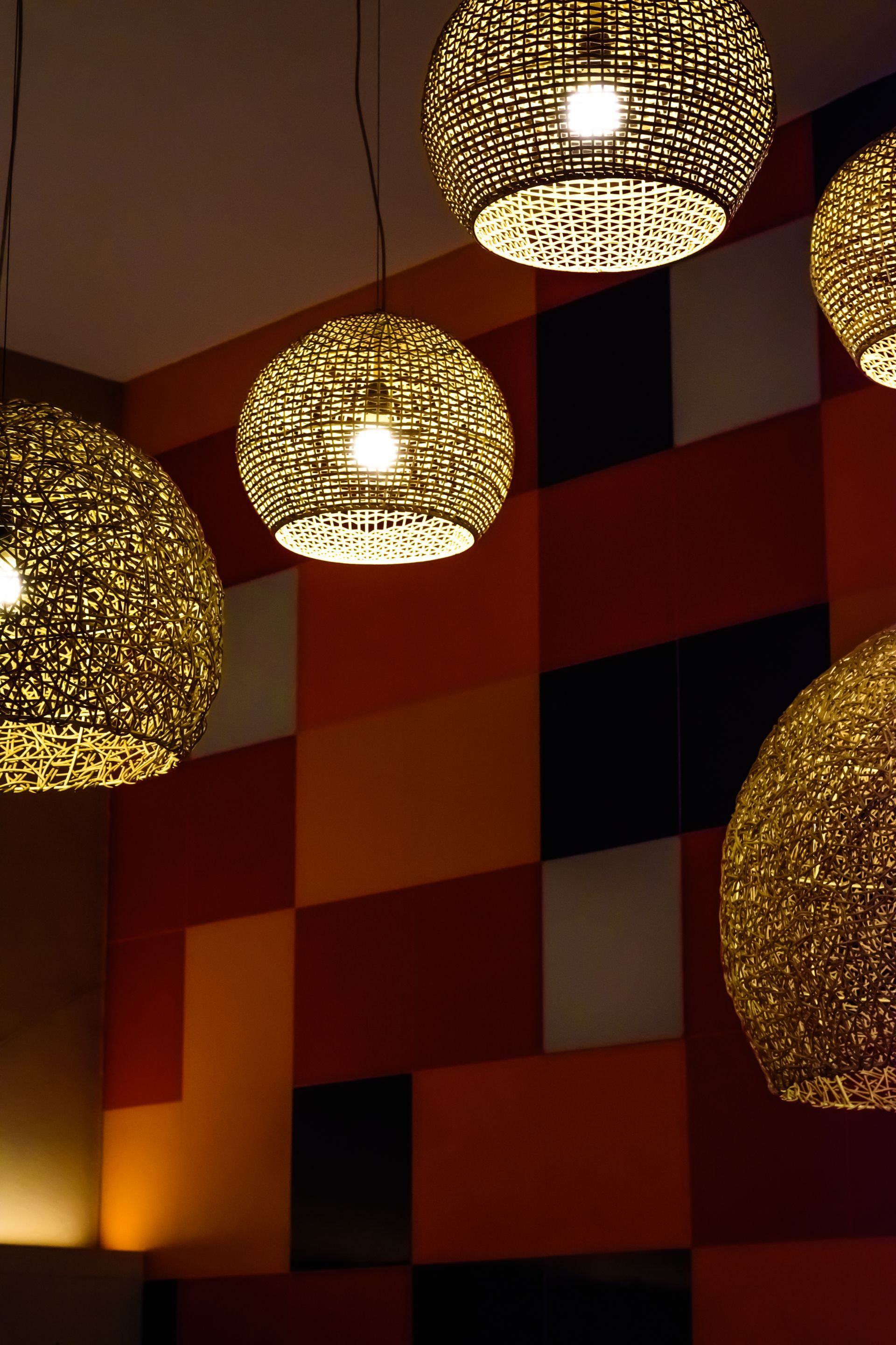 a bunch of lamps hanging from the ceiling in front of a checkered wall