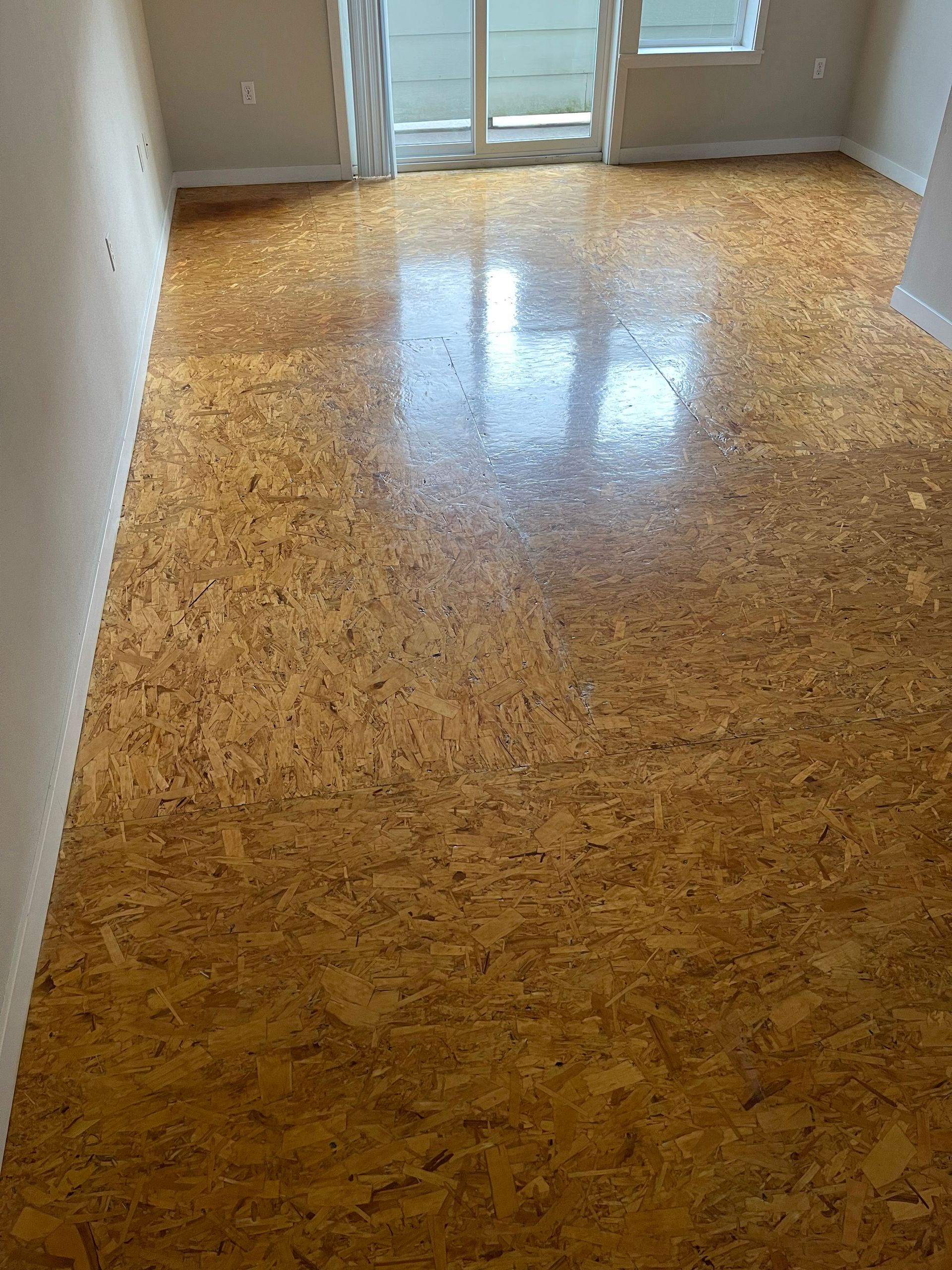 A living room with a cork floor and a sliding glass door.