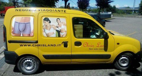 un furgone giallo con scritto Negozio Viaggiante con le immagini di un uomo in mutande e due donne che indossano della biancheria intima
