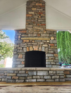 Stone fireplace with arched opening, built into a covered outdoor space.