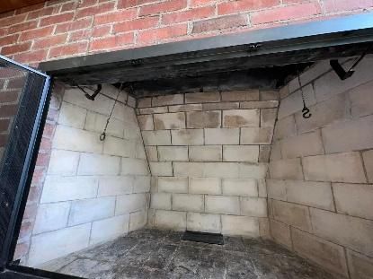 Fireplace interior with white brick walls, red brick surround, and black metal components.
