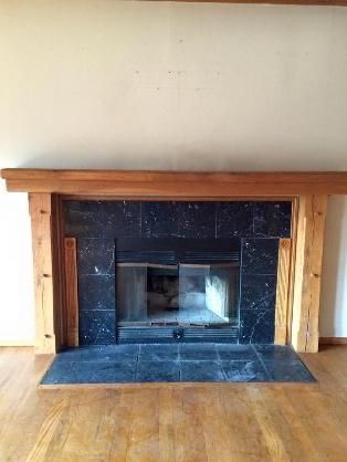 Fireplace with black tile surround, wooden mantel, and glass doors.