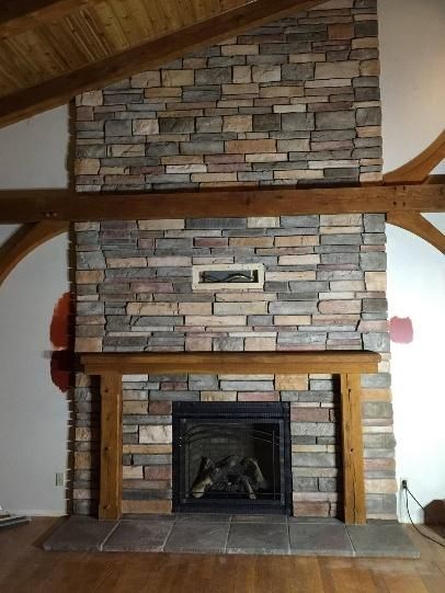 Stone fireplace with a wooden mantle and beam details in a room.