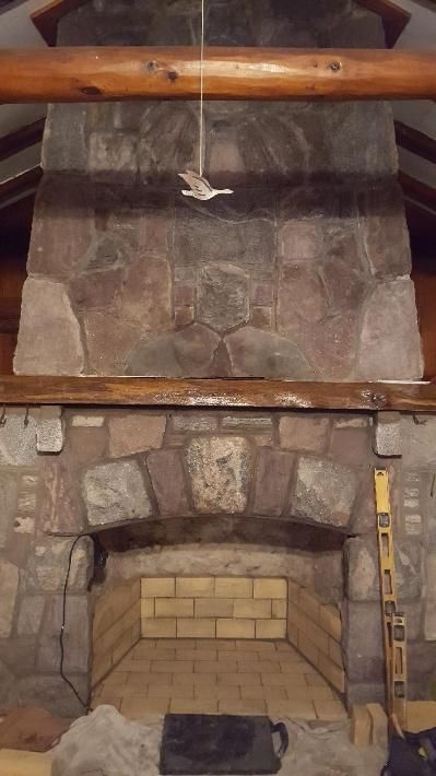 Stone fireplace with a brick firebox, wooden beams, and a decorative bird.