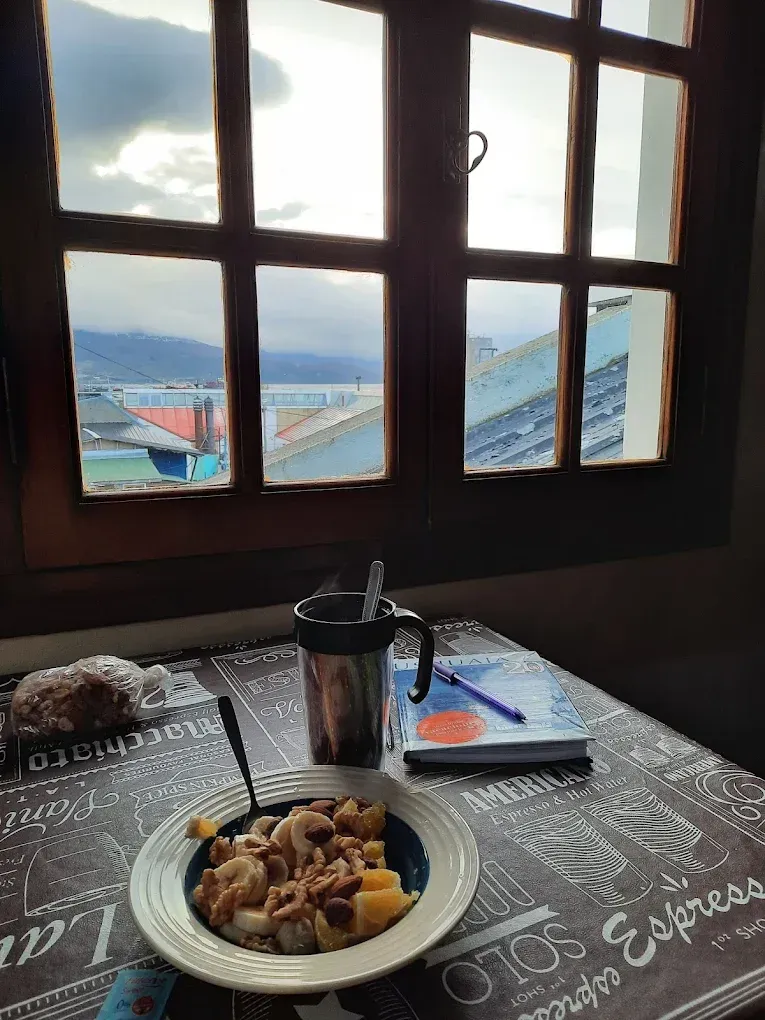 Desayuno en una mesa junto a la ventana, con vistas a las montañas nevadas y los tejados.