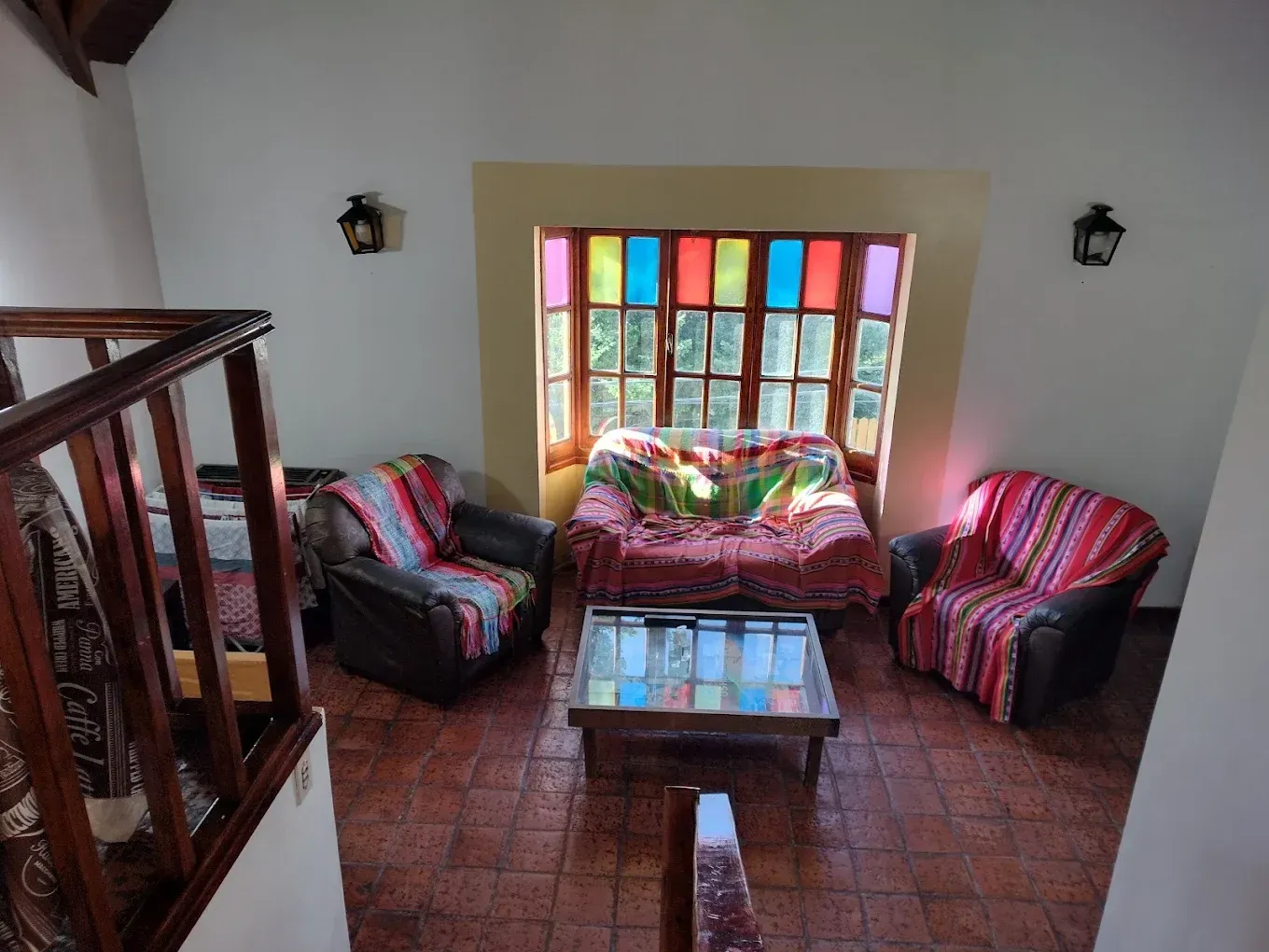 Sala de estar colorida con dos sillones a rayas, una mesita, un sofá y una vidriera.