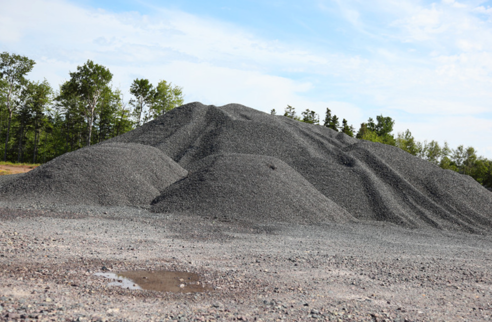 A large pile of #89 gravel is sitting on top of a dirt field.