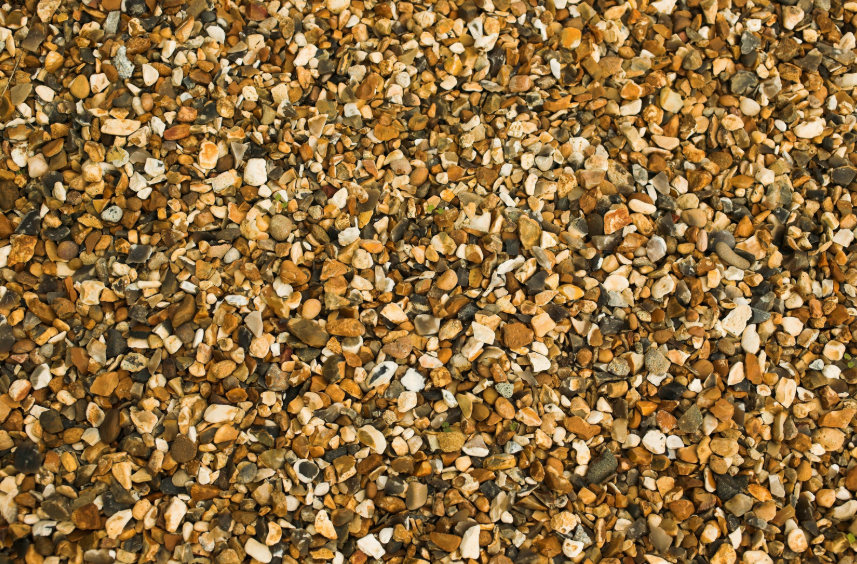 A close up of a pile of gravel on the ground, each mixed with white and brown colors