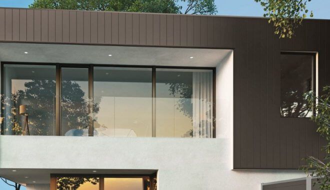 Modern huis met een bruine en witte gevel en grote ramen.