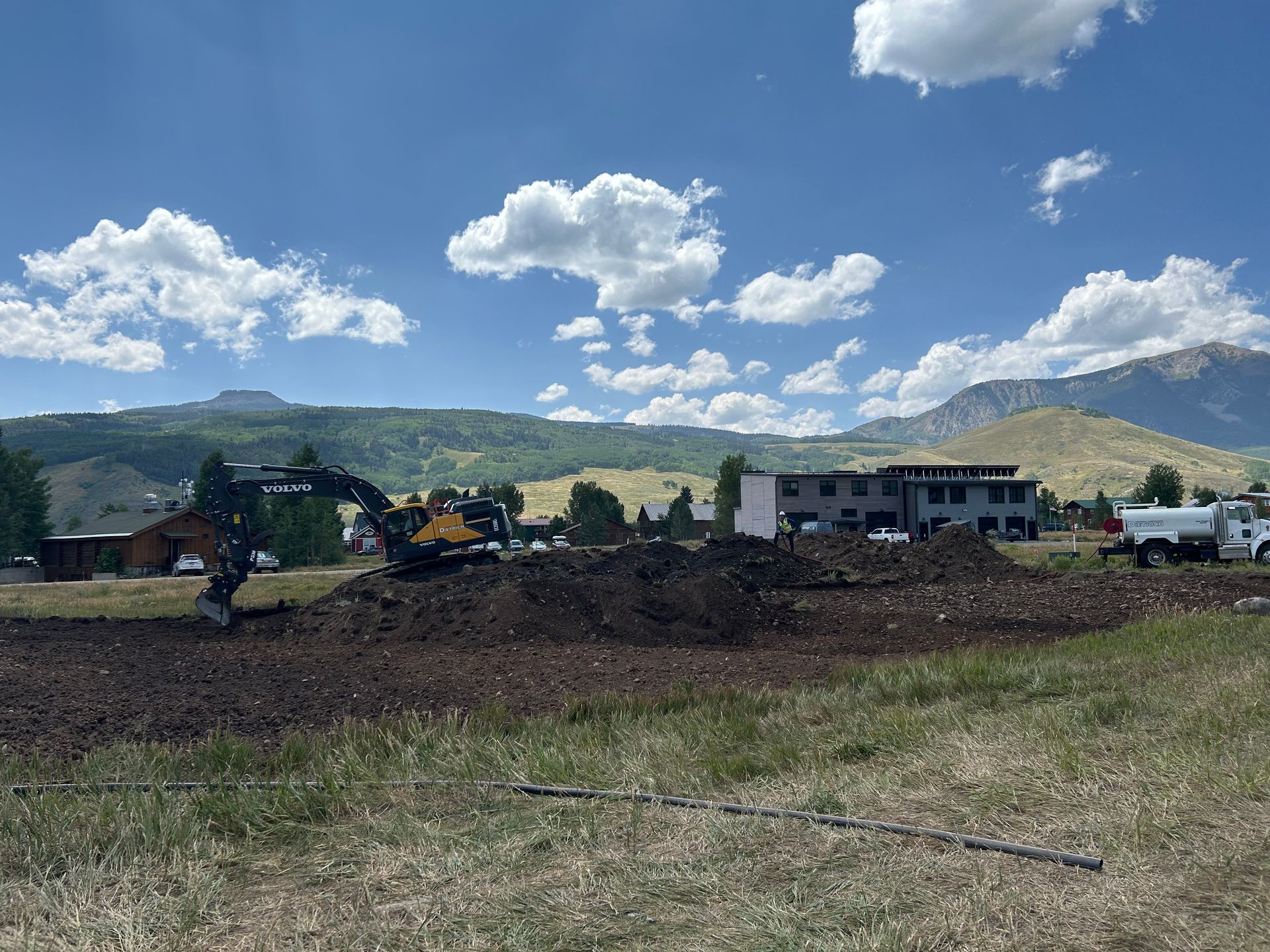 a large pile of dirt is being excavated in a field with mountains in the background .