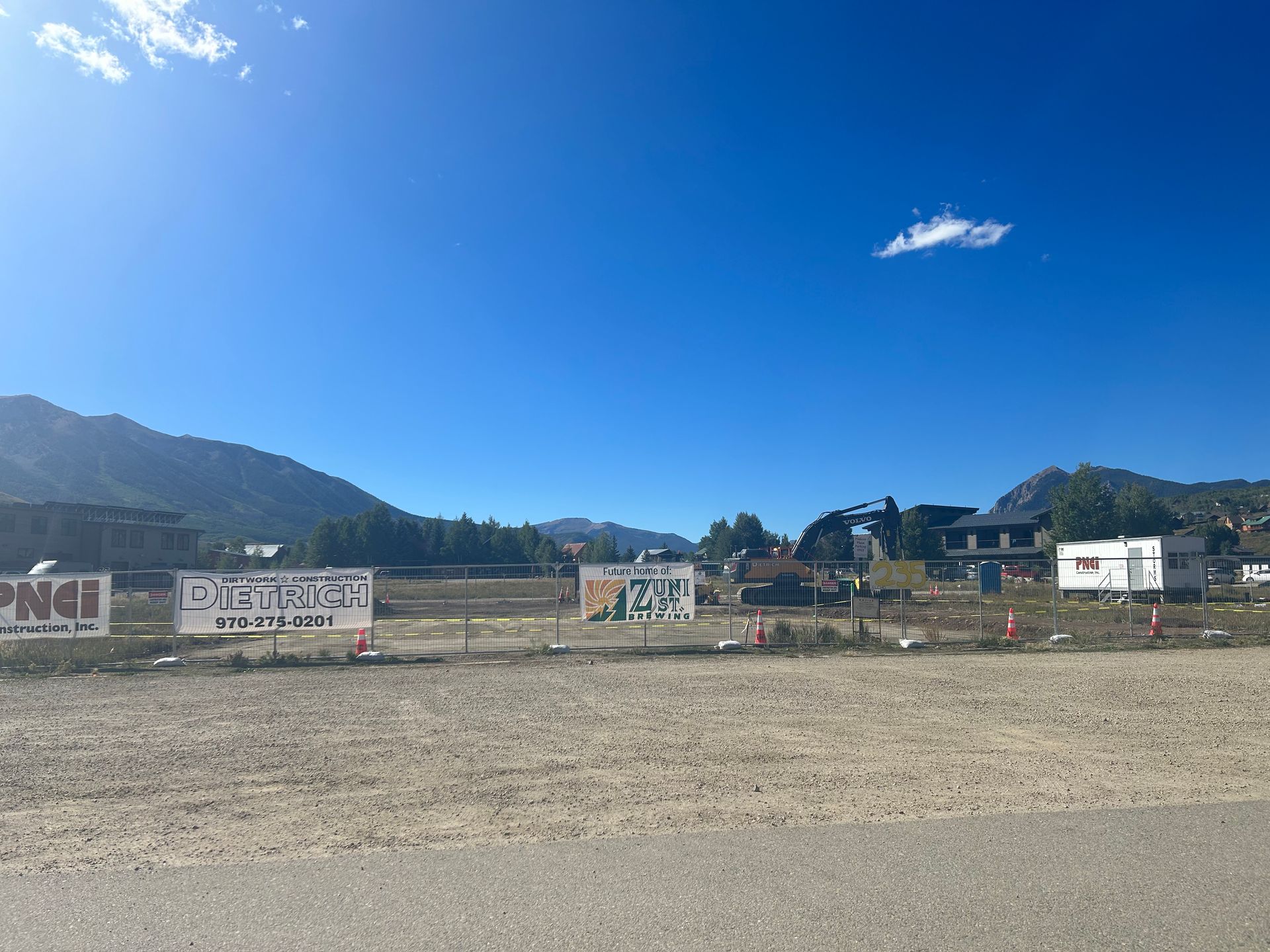 A dirt road with a lot of signs on it and mountains in the background.
