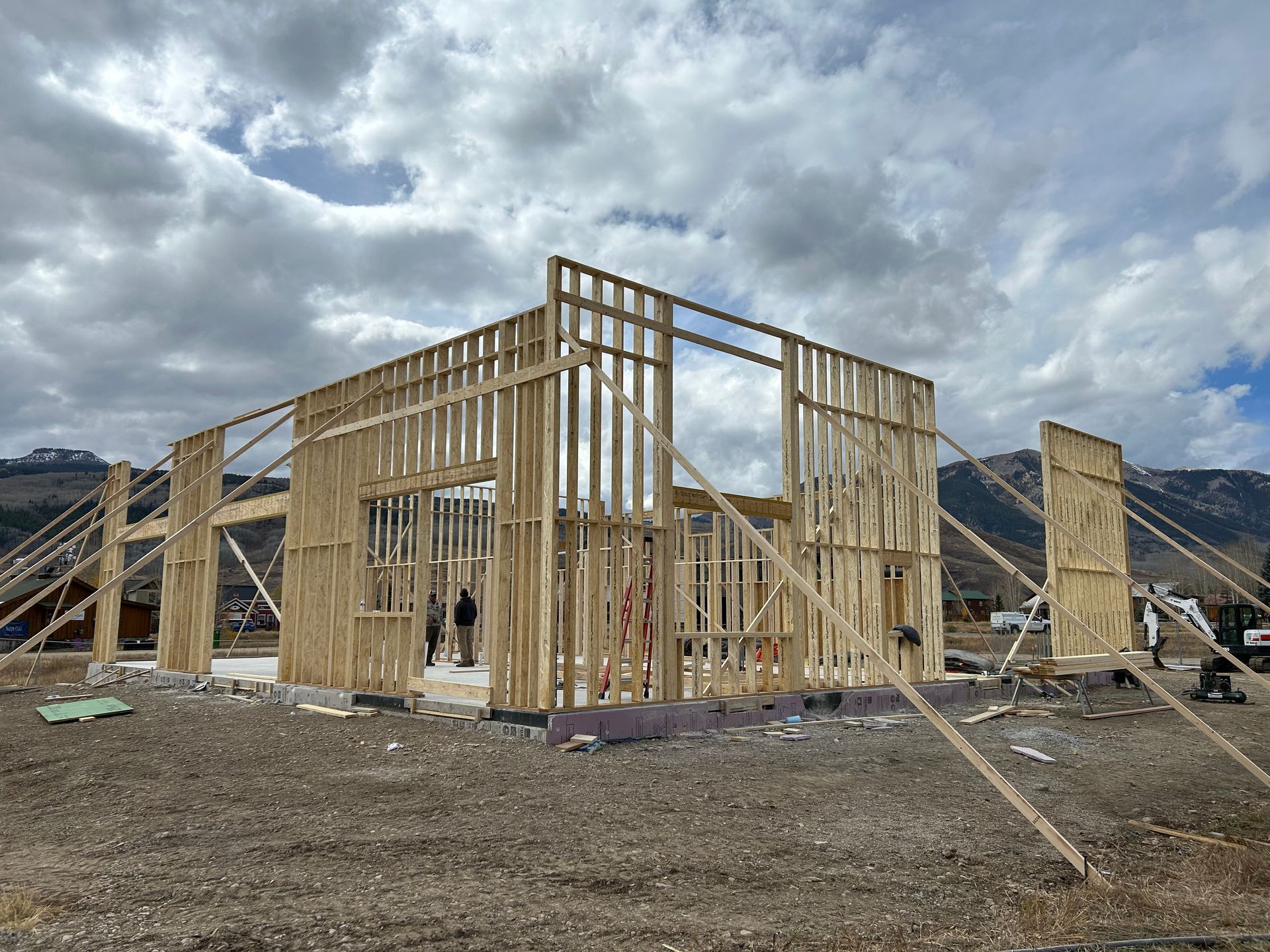 a house is being built in a field with mountains in the background .