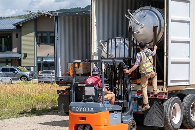 A man is loading a container with a forklift.