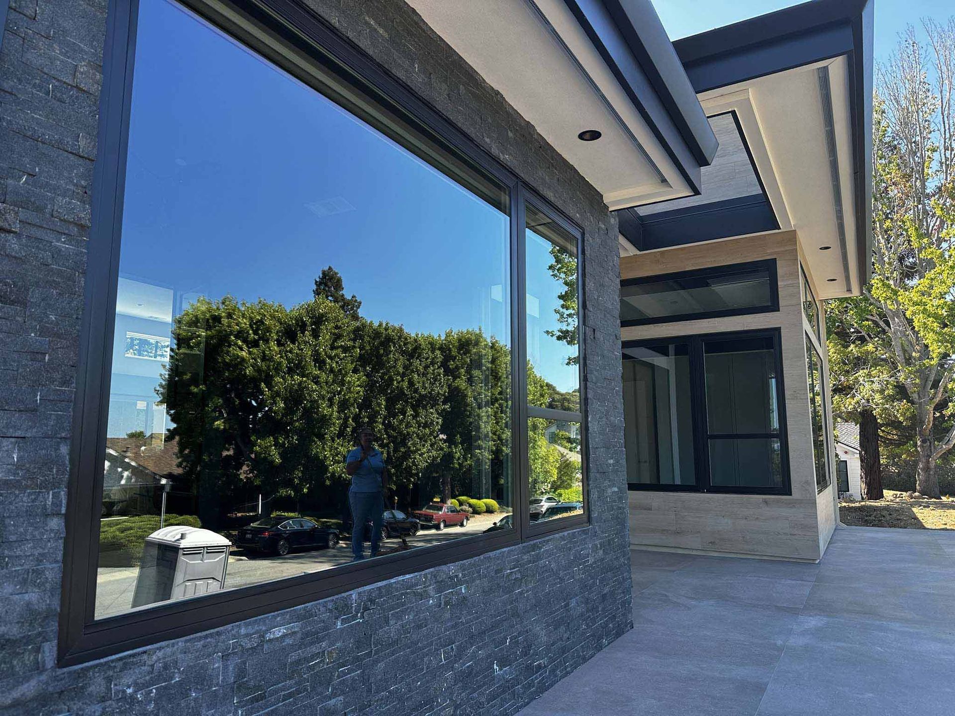 A large window on the side of a building with trees reflected in it.