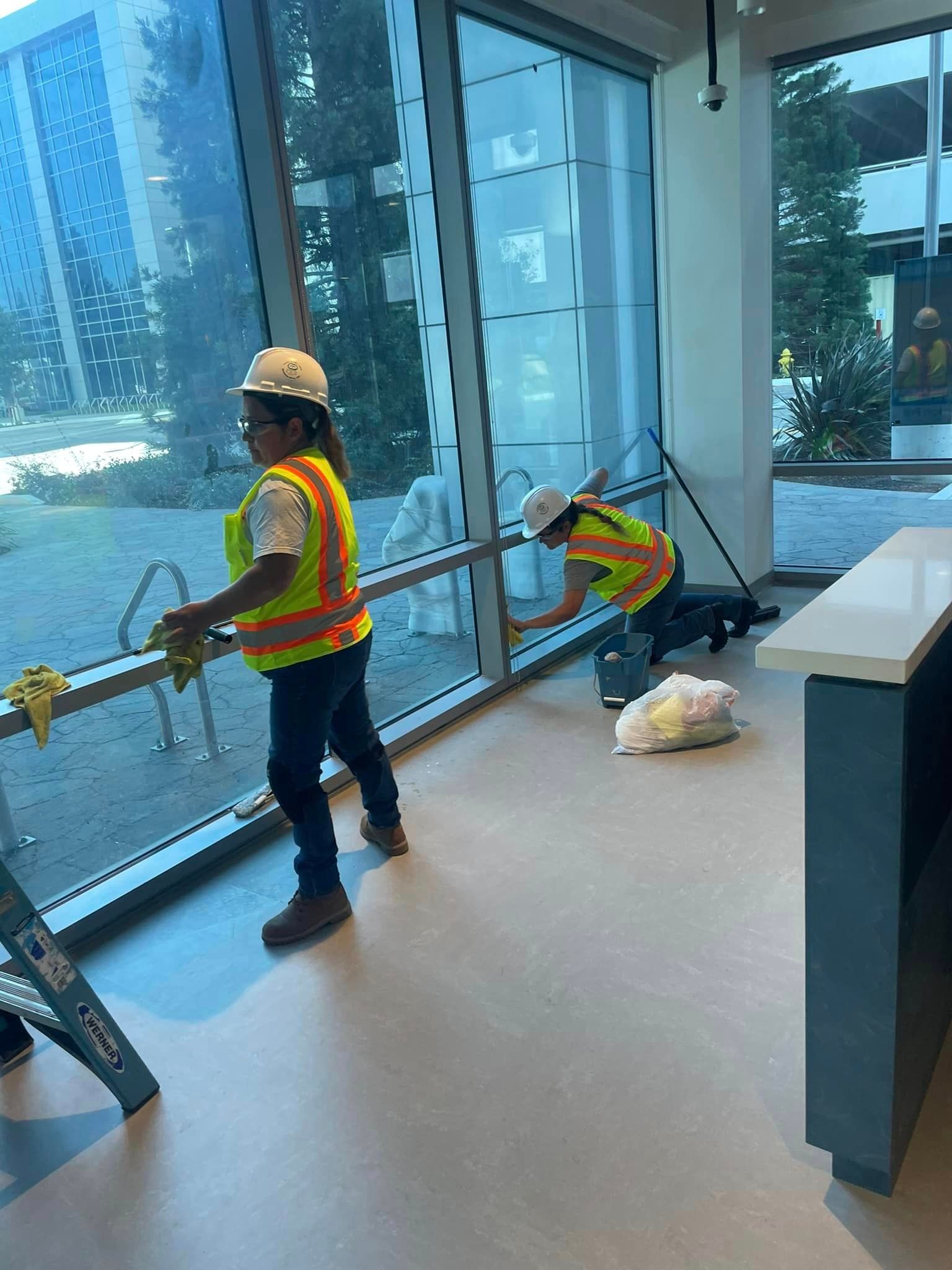 Two workers are cleaning windows in a building.