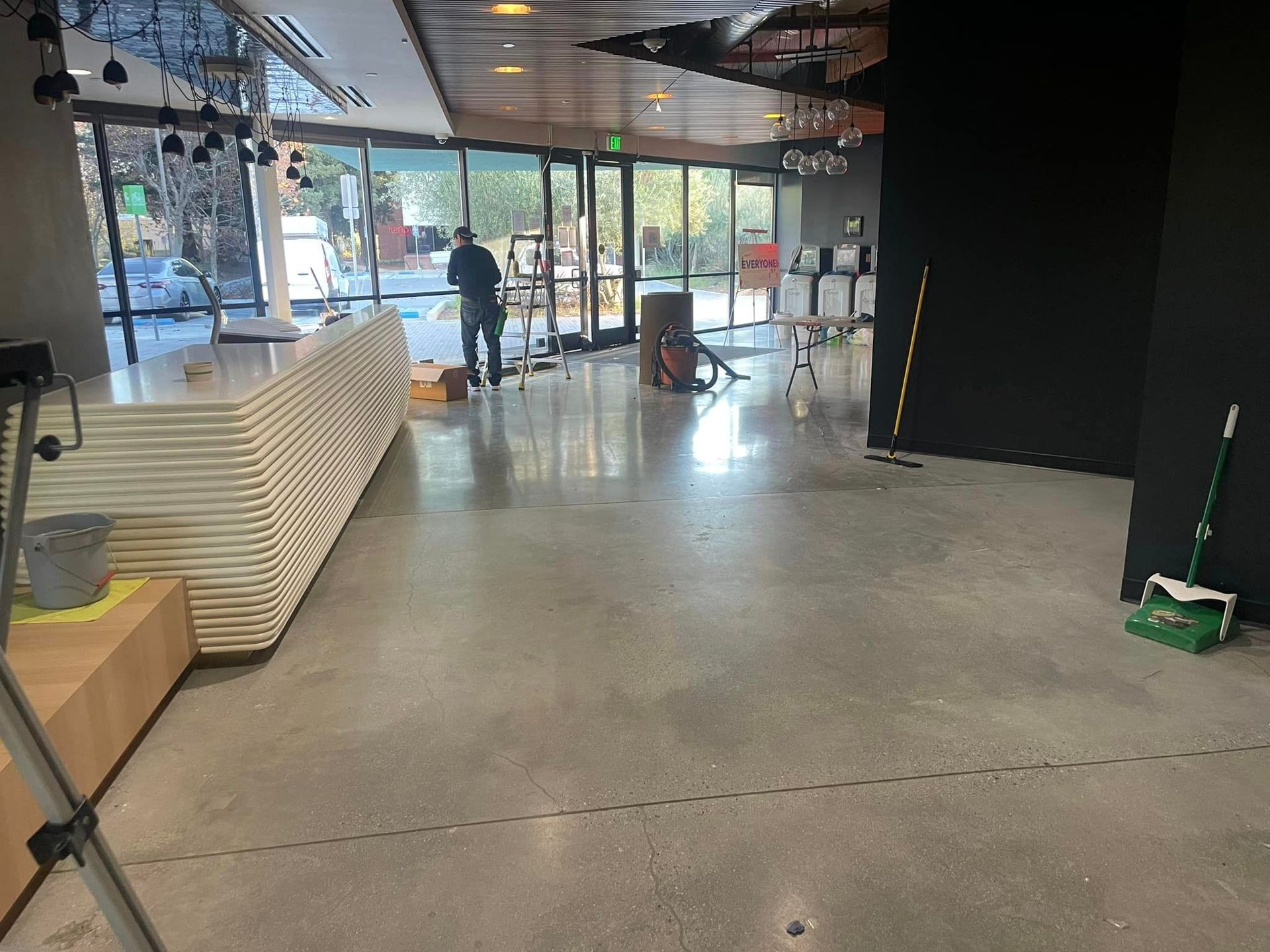 A man is standing in an empty room with a green mop.