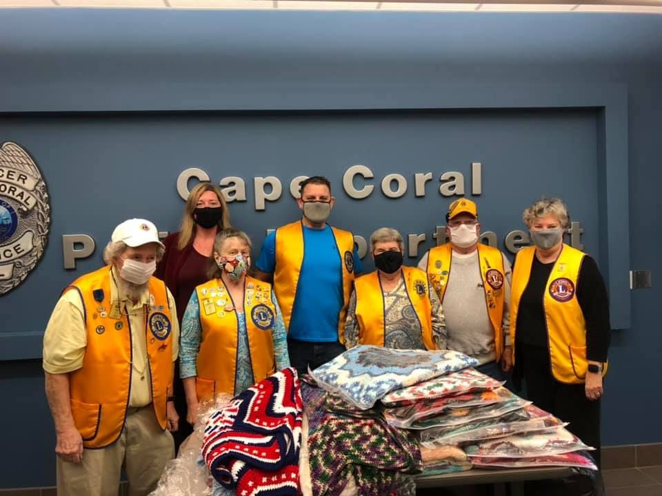 A group of people wearing masks are standing in front of a sign that says cape coral.