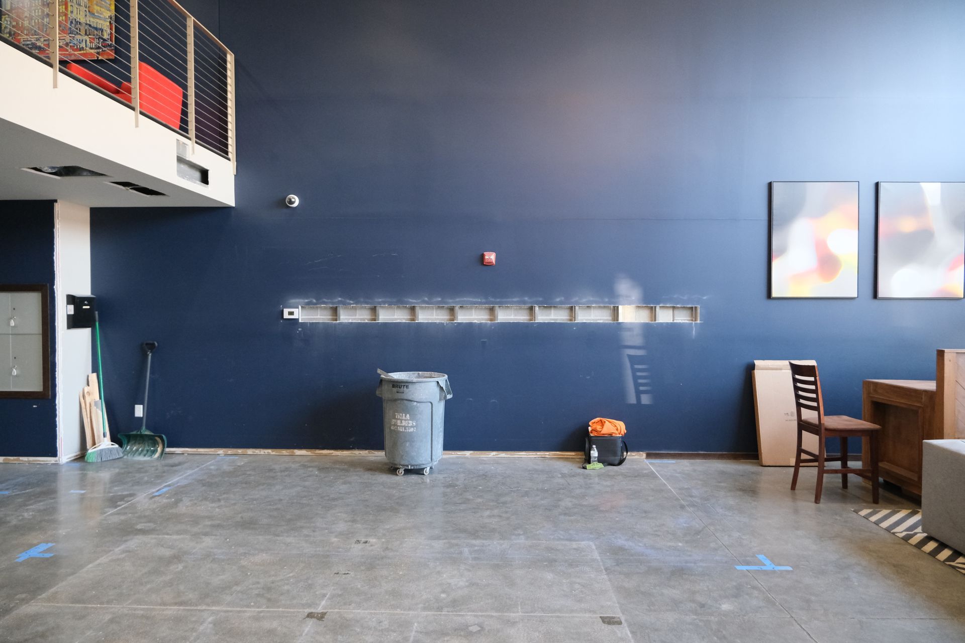 An empty room with a blue wall and a trash can