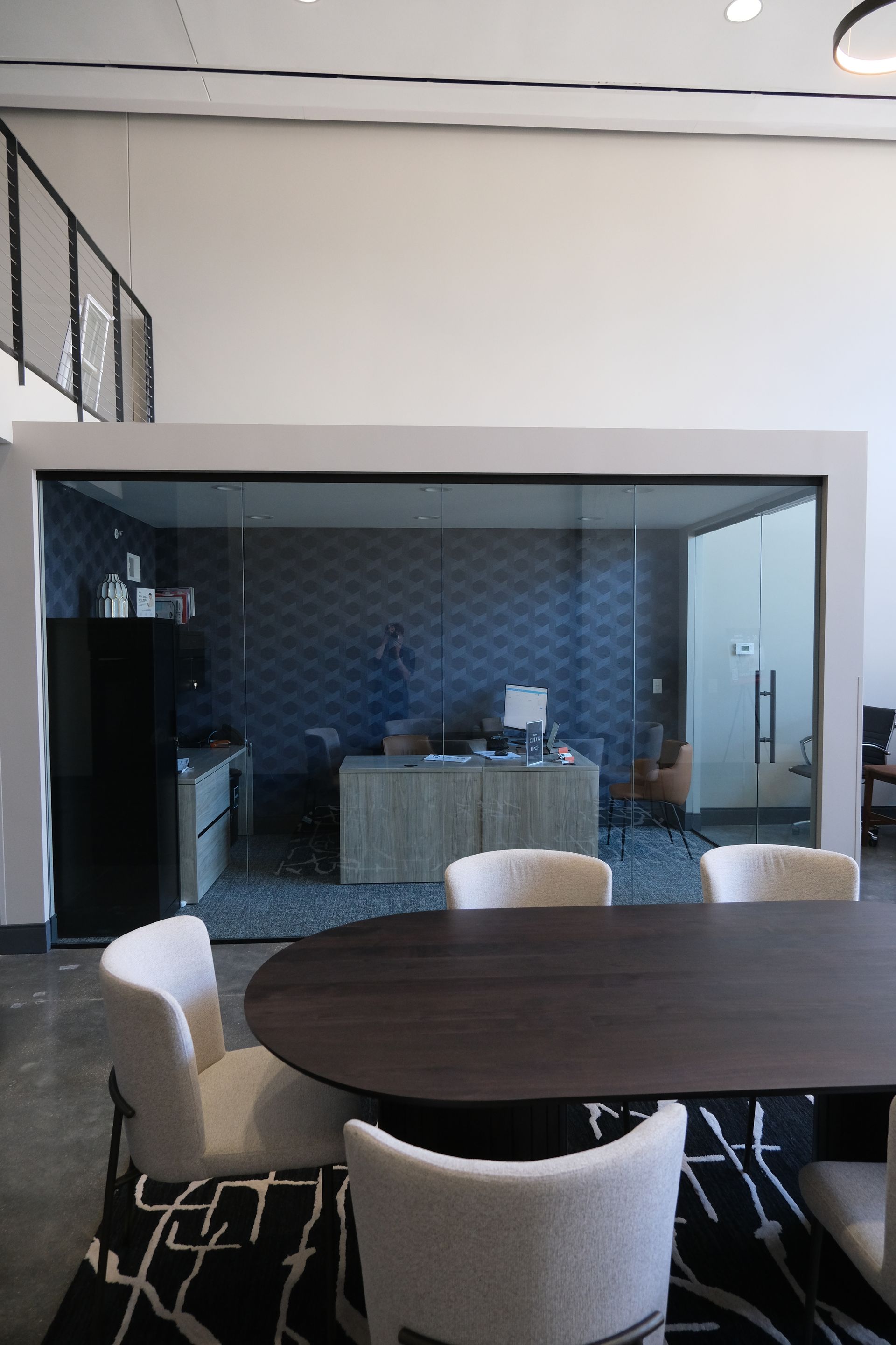 A conference room with a round table and chairs in front of a glass wall.