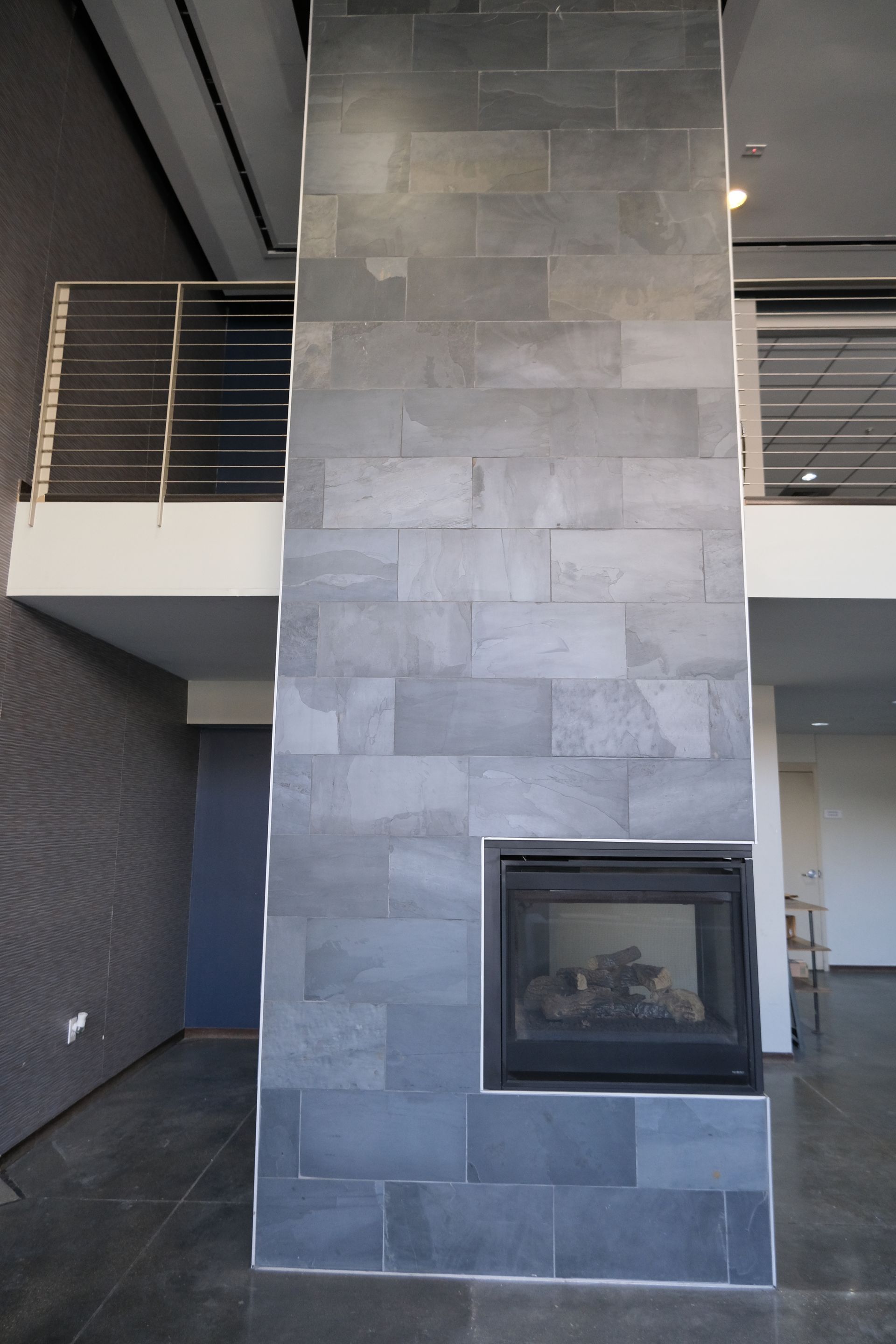 A fireplace in the middle of a room with a balcony