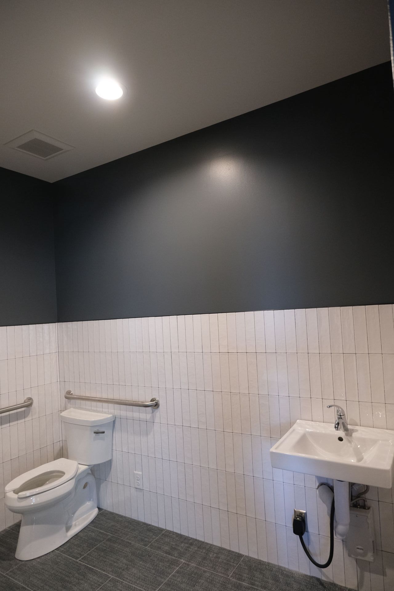 A bathroom with a toilet , sink , and black walls.