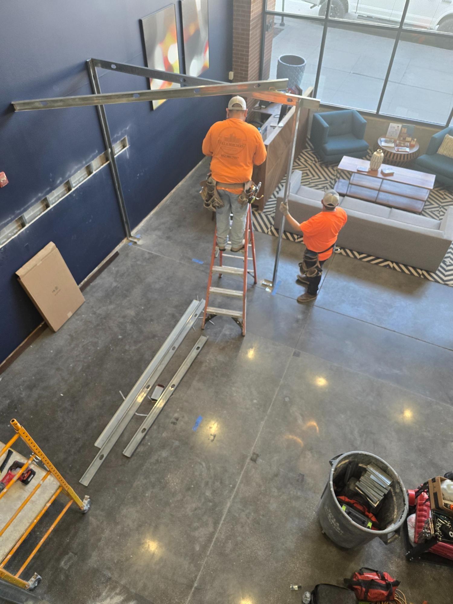 Two men are working on a ladder in a room.