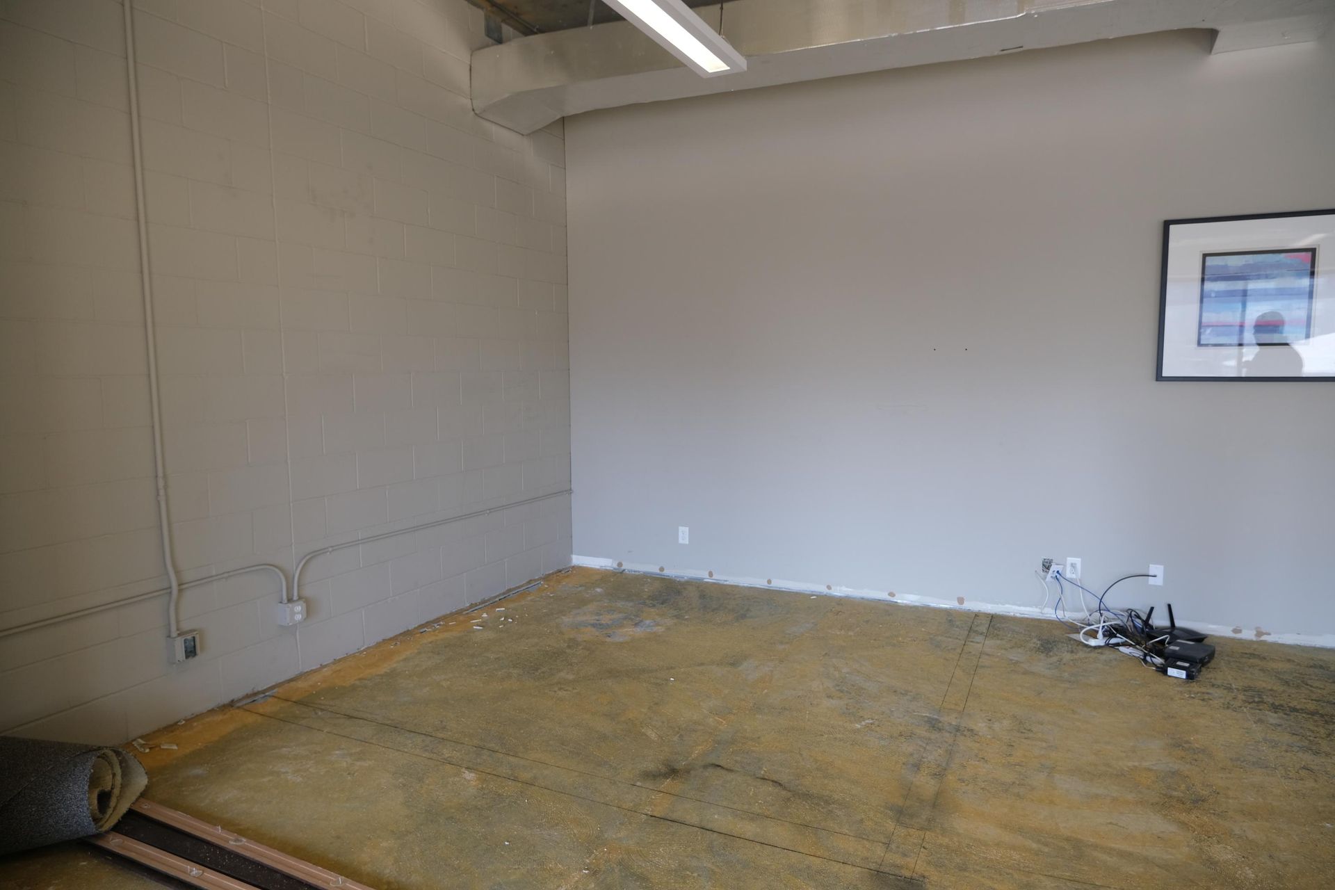 An empty room with a picture on the wall and a picture on the floor.