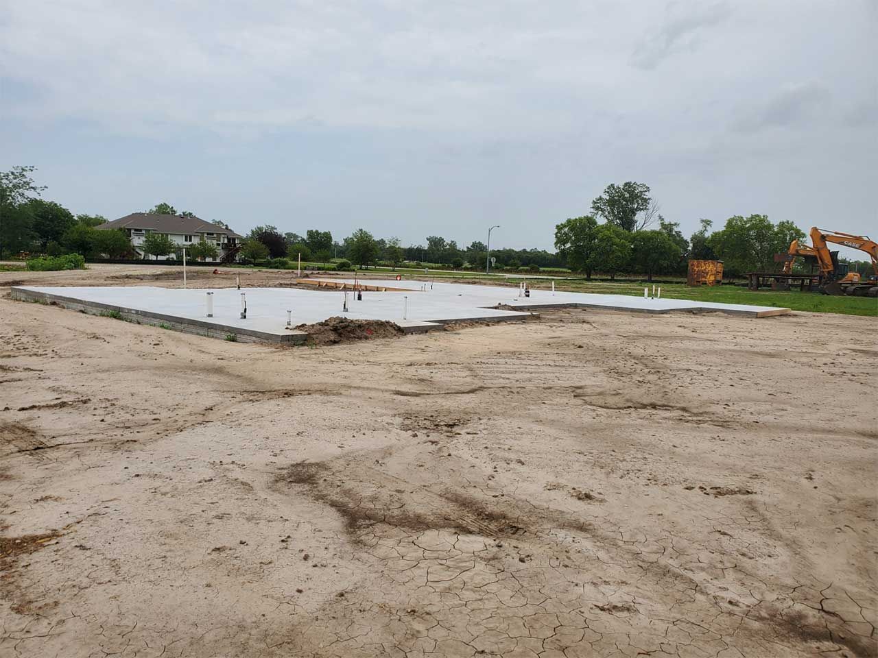 A large dirt field with a house in the background.