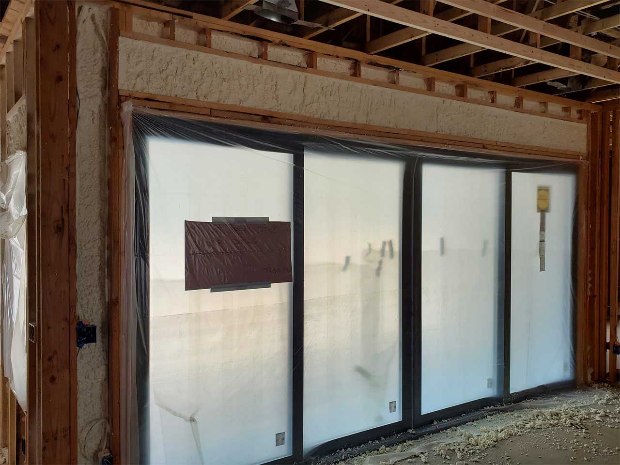 A house is being built and the windows are covered in plastic.