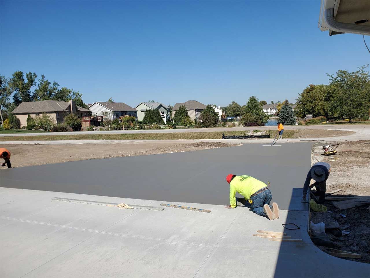 A group of construction workers are working on a concrete driveway.