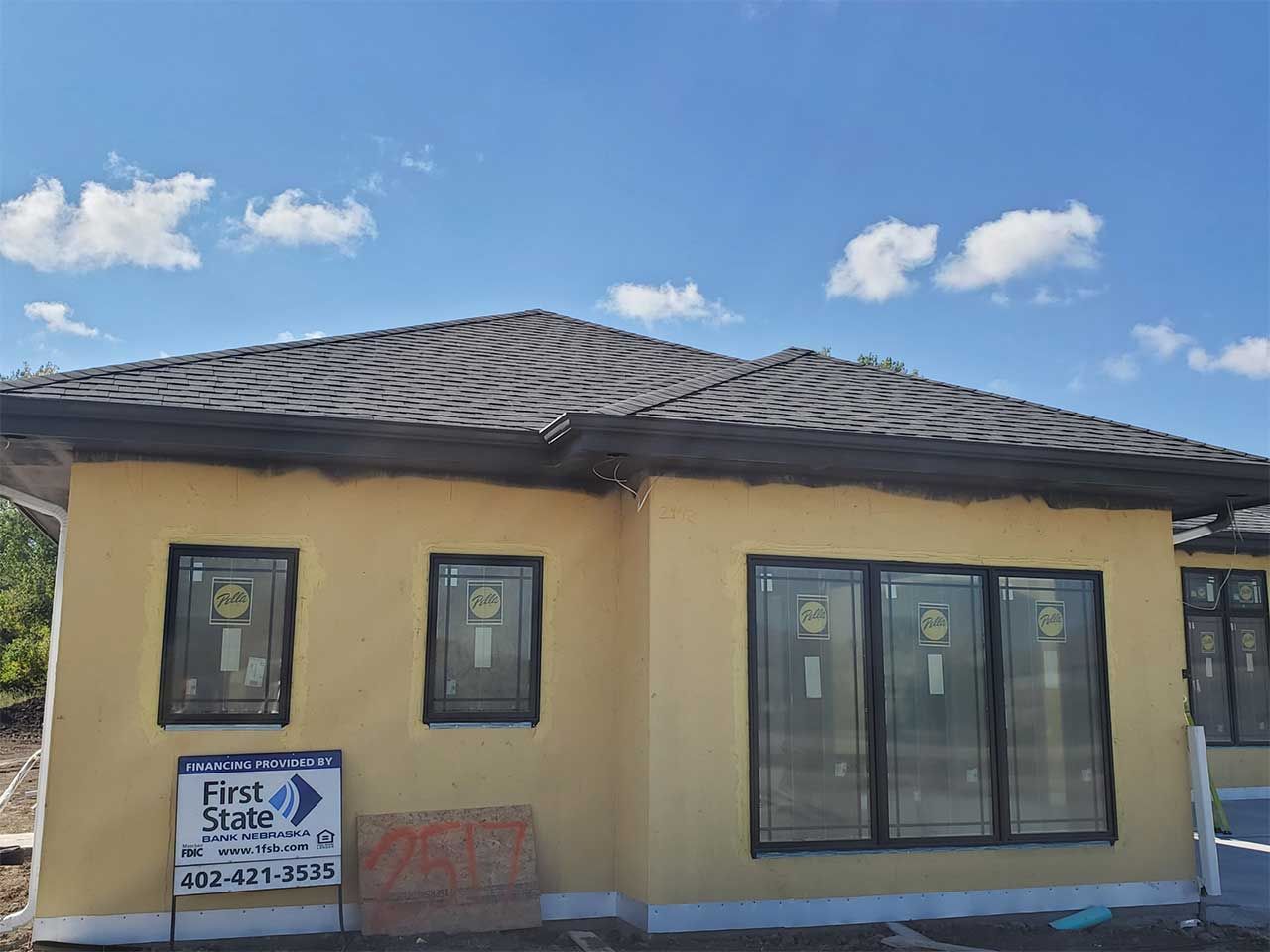 A yellow house with a black roof is being built.