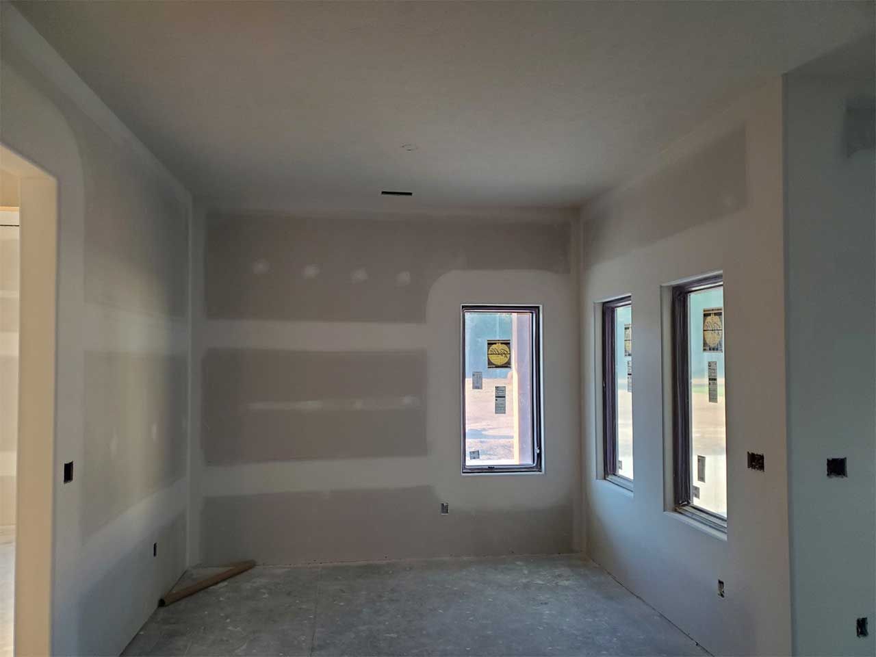 A room with a lot of windows and drywall on the walls.