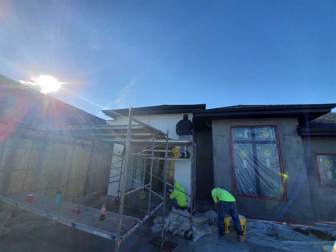 A group of construction workers are working on the side of a house.